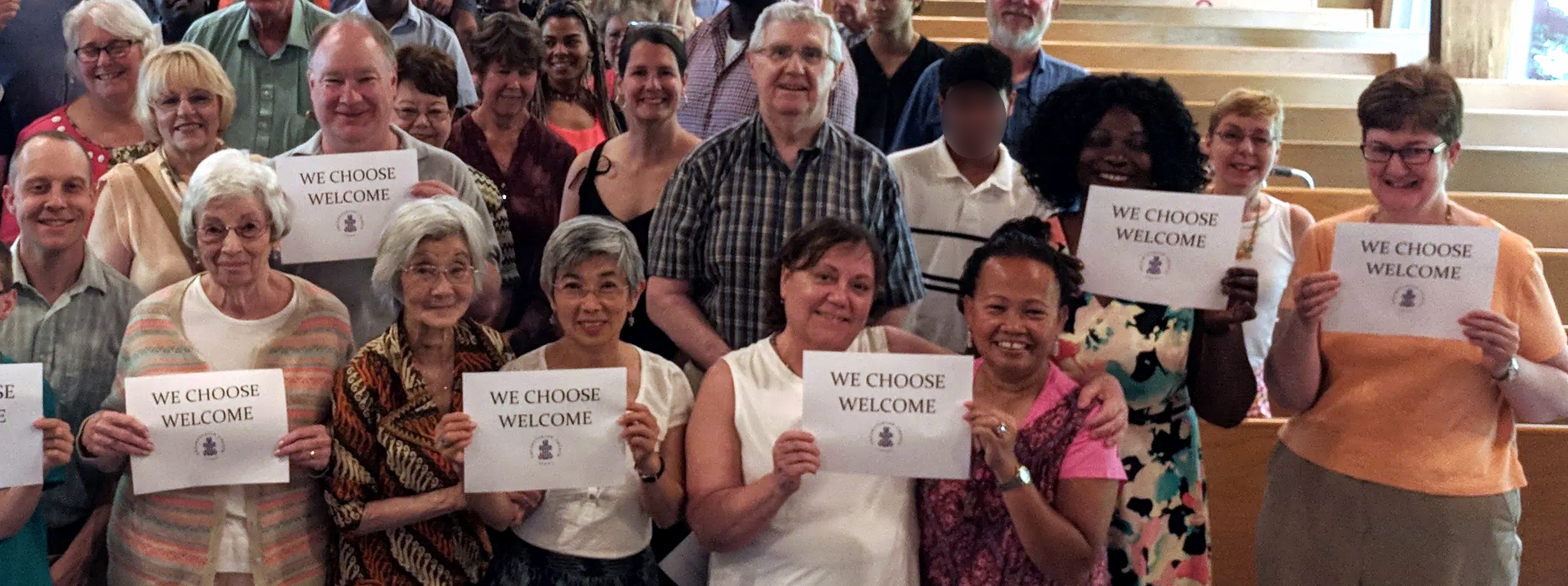 Church members hold signs saying "we choose welcome"