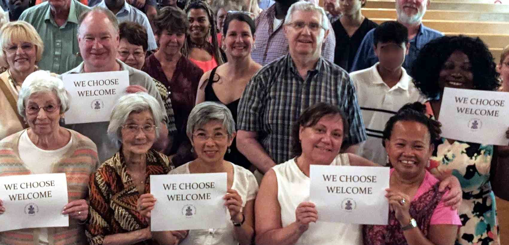 Church members holding signs saying "We Choose Welcome."
