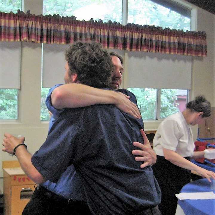 Men hugging in Fellowship Hall