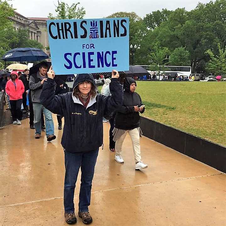 Person holds sign saying "Christians for Science"go