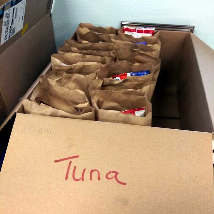 Box full of bagged lunches labeled "Tuna"