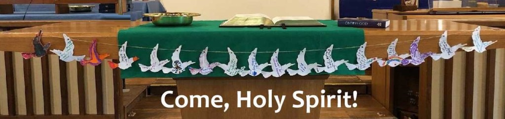 Communion table decorated with paper doves and title Come, Holy Spirit.